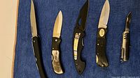Top view of all 5 folding pocket knives showing different handle designs and blade types.