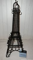 Front view of the black metal Eiffel Tower jewelry stand showing multiple hooks and mesh detail.