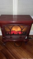 Front view of the Duraflame electric fireplace space heater with the ember flame effect on.
