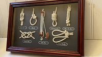 Full view of framed sailor's knots display showing various tied knots and labels on dark background