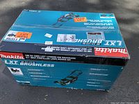 Closed Makita cardboard box showing LXT Brushless 21-inch self-propelled lawn mower graphics and branding