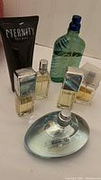 Photo showing six perfume and grooming items including two Calvin Klein Eternity spray bottles, one black tube, one small clear spray bottle, green Tommy Bahama bottle, and clear oval spray bottle.