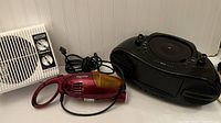 Photo showing Thermflo white wall-mounted space heater, red Monster handheld vacuum cleaner, and black DVD boombox together on a shelf.