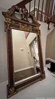 Full view of the vintage wall mirror showing its size and overall ornate frame design with gold accents and dark wood.