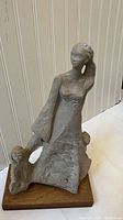 Full view of sculpture showing woman with children on wooden base