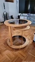 Angled view of the oak side table showing all three tiers with glass inserts and the swing-out middle tier partially deployed.