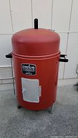 Front view of the round red Char-Broil smoker showing side handles, charcoal door, and legs.