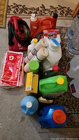 Photo showing red Dirt Devil handheld vacuum, various bottles of cleaning liquids, disposable cups, paper towels, dirt devil dust bags, and bottled water.