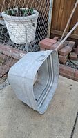 Galvanized metal bucket placed on ground near fence and bricks