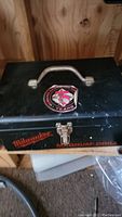 Closed view of black Milwaukee toolbox showing handle, latch, and branding sticker