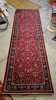 Full length view of red and blue Persian style runner rug on concrete floor