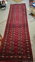 Full length view of the red runner rug laid out on the floor, showing overall design and condition