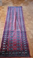 Full length view of the red runner rug with repeating medallion pattern and decorative borders.