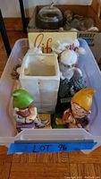 Top-down and angled view of assorted decorative figurines in plastic bin, including elf bookends, angel figures, cherub, and planter