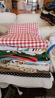 Stack of various folded tablecloths and runners with different patterns and materials shown from side angle