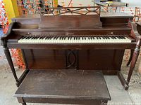 Front view of Baldwin Acrosonic upright piano and matching bench, showing the keyboard, music stand, and legs