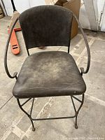 Front view of vintage brown leather bar stool showing seat, backrest, and metal frame with visible wear