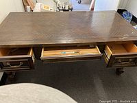Top view of banker's desk with three drawers open, showing parquet wood surface and original brass handles on front drawers.