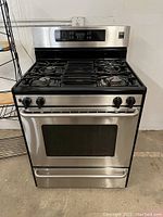 Front view of stainless steel gas stove showing cooktop, control panel and oven door