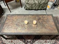 Top-down view of the coffee table showing iridescent metal surface with patinated finish and decorative swirling pattern.