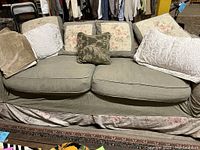 Front view of shabby chic sofa with slipcover and multiple decorative pillows and throws arranged on it.