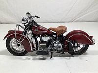 Side view showing detailed 1942 Indian 442 motorcycle replica with maroon body and brown leather seat, chrome parts and black wheels.