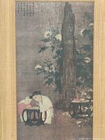 Close-up of a framed Asian art print showing traditional figures and a tall rock with flowers in muted colors, some visible cracks and surface wear