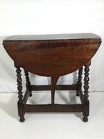 Full view of drop leaf side table with leaves down, showing front and legs.