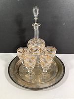 Front view of hand painted glass decanter with stopper, four matching glasses with gold hand painted decoration, placed on Cornwall EPNS silver-plated platter.