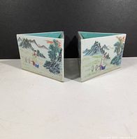 Two triangular ceramic planters side by side showing exterior landscape scenes