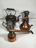 Top view of all five mixed metal items arranged on white background showing different kettle styles and handheld spray bottle.
