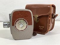 Keystone Capri Deluxe 8mm movie camera shown with leather carrying case, side ISO and shutter speed dial visible.