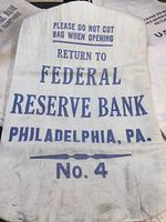 Close-up photo of Federal Reserve Bank Philadelphia coin bag No. 4 with printed instructions and bank name in blue lettering on white canvas.