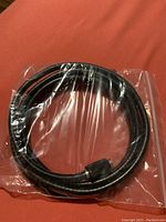 Photo of a black CATVR cable coiled and sealed in clear plastic bag on an orange surface.