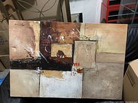 Photo of an abstract painting in earthy tones with textured surfaces and mixed materials on canvas.