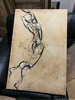 Photo of a wooden picture frame featuring an abstract black line human form on a natural wood background.