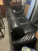 Side view of black leather sofa showing seat cushions and armrest.
