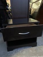 Photo of the small dark wood cabinet showing the drawer partially open and open shelf below