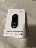 Front of retail box showing image of Simply Smart Video Doorbell and branding with compatibility icons for Hey Google, Alexa, Apple HomeKit, SmartThings.