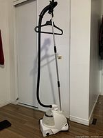Full view of Conair garment steamer showing the white base, curved black hose, extender pole, and hanger attachment.