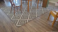 Overall view of rectangular grey and cream geometric flatweave area rug placed under dining chairs and table