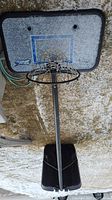 Full view of portable basketball hoop system including base, pole, rim, net and backboard lying down.