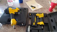 Two Stanley FatMax pneumatic nailers including one 18 gauge brad nailer and one 16 gauge air nailer, each in its carrying case, placed on a counter with other miscellaneous items.