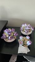 Three Royal Adderly porcelain floral arrangements on a black surface, showing overall lot contents and relative sizes.