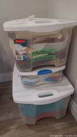 Stack of three clear plastic storage bins with white lids containing quilting fabrics and batting, labeled on front: 'Quilting fabric 1 cut out quilt, Batting for quilts'