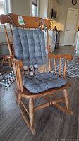 Full view of the wood vintage rocking chair with gray tufted cushions on seat and back.