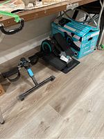 Shows one of the seated elliptical machines near a Cubii box, mainly black with turquoise accents.