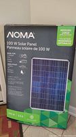 Full boxed NOMA 100 Watt Solar Panel in black and green packaging showing product details and usage illustrations.