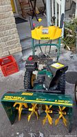 Front view of entire snow blower showing auger housing, handles, headlight