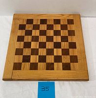Photo showing the handmade wood chess/draft board with alternating light and dark squares in a wooden frame.